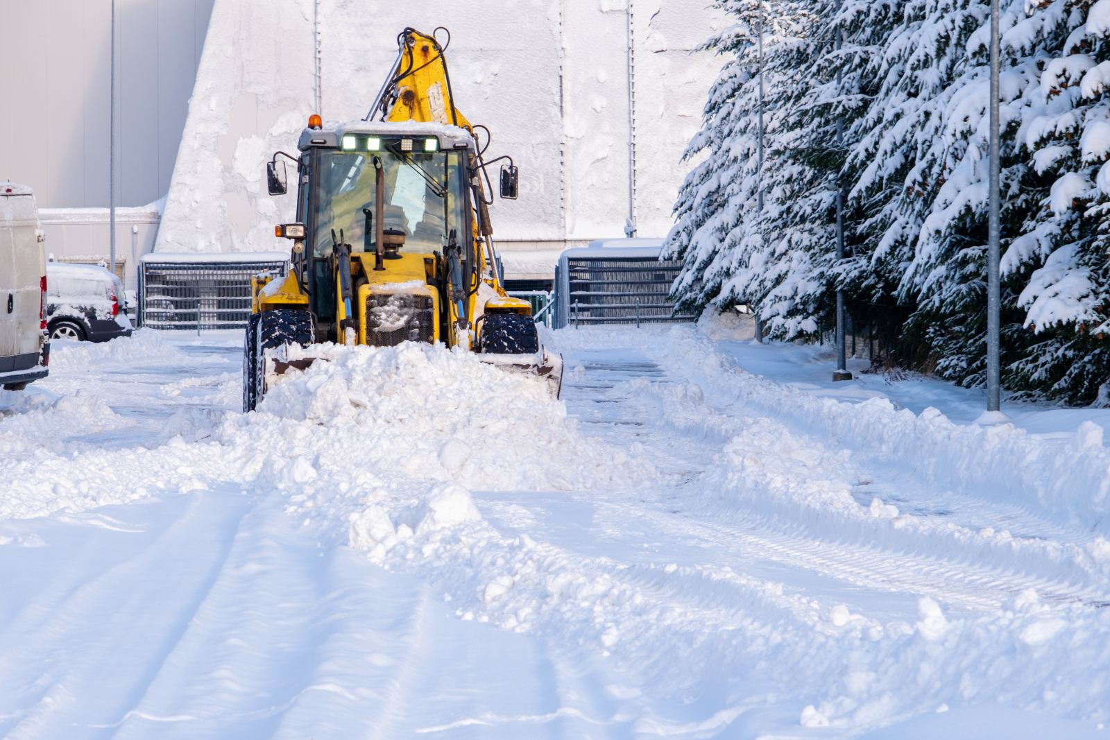 Backhoe pushing snow out of a commercial access lane