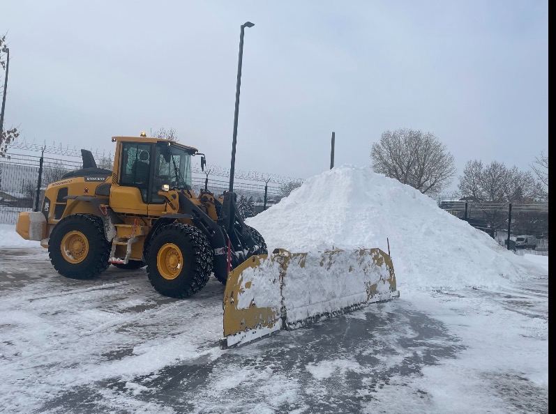 Volvo loader with pusher blade on a commercial lot