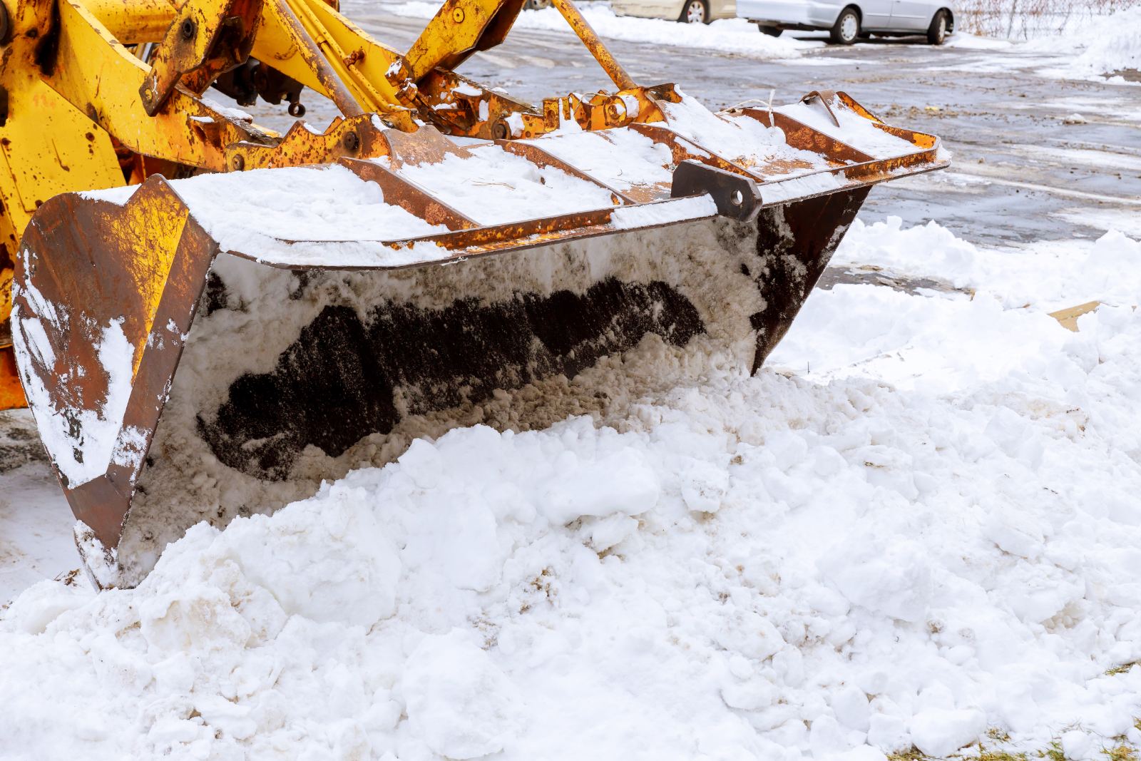Loader bucket loaded with snow on a cleared lot